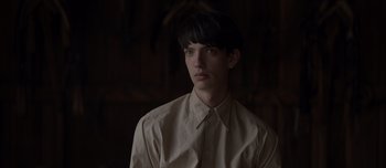 Movie still from “The Power of the Dog” (2021), directed by Jane Campion – A young man with dark hair wearing a white shirt; Close Up shot, Over the shoulder angle