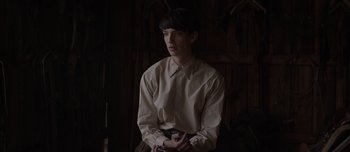 Movie still from “The Power of the Dog” (2021), directed by Jane Campion – A man in a white shirt is sitting down; Medium shot, Over the shoulder angle