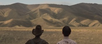 Movie still from “The Power of the Dog” (2021), directed by Jane Campion – Two men are looking out at a mountain range; Wide shot, Over the shoulder angle