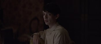 Movie still from “The Power of the Dog” (2021), directed by Jane Campion – A young man sitting in a dark room; Close Up shot, Low angle