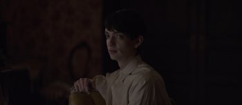 Movie still from “The Power of the Dog” (2021), directed by Jane Campion – A young man is sitting in a dark room; Close Up shot, Over the shoulder angle
