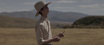 Movie still from “The Power of the Dog” (2021), directed by Jane Campion – A man in a cowboy hat holding a flower in his hand; Medium shot, Low angle