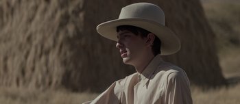 Movie still from “The Power of the Dog” (2021), directed by Jane Campion – A young man wearing a white hat and a tie; Close Up shot, Over the shoulder angle