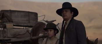 Movie still from “The Power of the Dog” (2021), directed by Jane Campion – A man and a boy wearing hats standing next to each other; Medium shot, Low angle