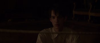 Movie still from “The Power of the Dog” (2021), directed by Jane Campion – A man in a white shirt is sitting in a dark room; Close Up shot, Over the shoulder angle