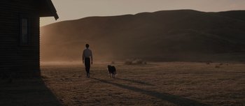 Movie still from “The Power of the Dog” (2021), directed by Jane Campion – A man and a dog are walking in a field; Extreme Wide shot, Low angle