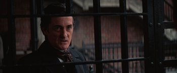Movie still from “The Prestige” (2006), directed by Christopher Nolan – A man standing behind a fence looking at the camera; Close Up shot, Over the shoulder angle