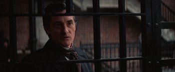 Movie still from “The Prestige” (2006), directed by Christopher Nolan – A man wearing a suit and tie behind a fence; Close Up shot, Over the shoulder angle