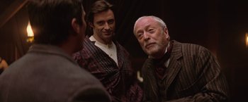 Movie still from “The Prestige” (2006), directed by Christopher Nolan – Two men and a woman are standing together; Close Up shot, Over the shoulder angle