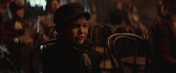 Movie still from “The Prestige” (2006), directed by Christopher Nolan – A young boy wearing a hat and a scarf; Close Up shot, Over the shoulder angle