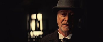 Movie still from “The Prestige” (2006), directed by Christopher Nolan – An older man wearing a hat and a suit; Close Up shot, Low angle