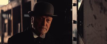 Movie still from “The Prestige” (2006), directed by Christopher Nolan – An older man wearing a hat and a suit; Close Up shot, Over the shoulder angle