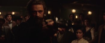 Movie still from “The Prestige” (2006), directed by Christopher Nolan – A man with long hair and a goatee is holding a gun; Close Up shot, Over the shoulder angle