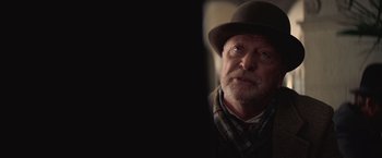 Movie still from “The Prestige” (2006), directed by Christopher Nolan – An older man wearing a hat and a plaid vest; Close Up shot, Over the shoulder angle