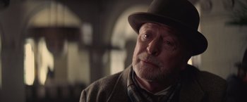 Movie still from “The Prestige” (2006), directed by Christopher Nolan – An older man wearing a hat and a sweater; Close Up shot, Over the shoulder angle