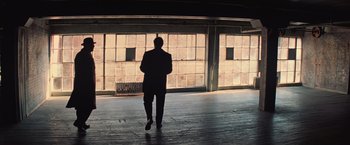 Movie still from “The Prestige” (2006), directed by Christopher Nolan – A man standing in front of an open garage door; Wide shot, High angle