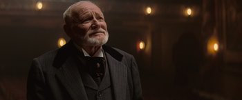 Movie still from “The Prestige” (2006), directed by Christopher Nolan – An older man in a suit and tie; Close Up shot, Low angle