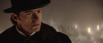 Movie still from “The Prestige” (2006), directed by Christopher Nolan – A person wearing a coat and hat; Close Up shot, Low angle
