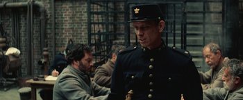 Movie still from “The Prestige” (2006), directed by Christopher Nolan – A man in a uniform is standing in front of a group of people; Medium shot, Low angle