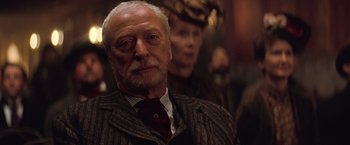 Movie still from “The Prestige” (2006), directed by Christopher Nolan – An older man wearing a suit and a tie; Close Up shot, Low angle