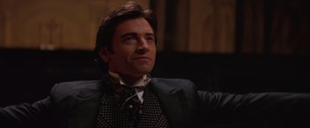 Movie still from “The Prestige” (2006), directed by Christopher Nolan – A person wearing a suit and tie; Close Up shot, Low angle