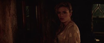 Movie still from “The Prestige” (2006), directed by Christopher Nolan – A woman in a white shirt is standing in a dark room; Close Up shot, Over the shoulder angle