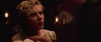 Movie still from “The Prestige” (2006), directed by Christopher Nolan – A woman sitting in front of a man with her hand on her chest; Close Up shot, Over the shoulder angle