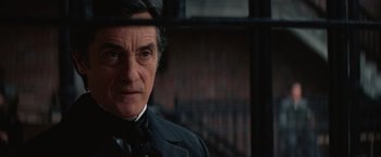 Movie still from “The Prestige” (2006), directed by Christopher Nolan – A person wearing a suit and hat; Close Up shot, Over the shoulder angle