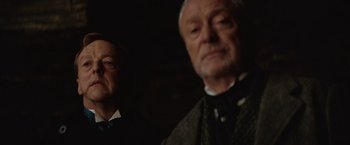 Movie still from “The Prestige” (2006), directed by Christopher Nolan – Two men in a dark room , one of whom is wearing a suit; Close Up shot, Low angle