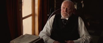 Movie still from “The Prestige” (2006), directed by Christopher Nolan – An older man sitting in a chair in front of a window; Close Up shot, Low angle
