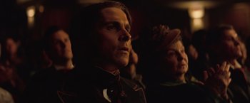 Movie still from “The Prestige” (2006), directed by Christopher Nolan – A person wearing a suit and tie; Close Up shot, Low angle