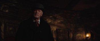 Movie still from “The Prestige” (2006), directed by Christopher Nolan – An old man wearing a hat and a coat; Close Up shot, Over the shoulder angle