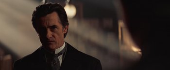 Movie still from “The Prestige” (2006), directed by Christopher Nolan – A person wearing a suit and tie; Close Up shot, Low angle