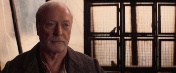 Movie still from “The Prestige” (2006), directed by Christopher Nolan – An older man with a beard and mustache; Close Up shot, Over the shoulder angle