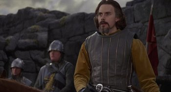 Movie still from “The Princess Bride” (1987), directed by Rob Reiner – A man with a beard wearing a gray and yellow outfit; Medium shot, Low angle