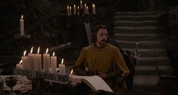 Movie still from “The Princess Bride” (1987), directed by Rob Reiner – A man sitting at a table with candles in front of him; Medium shot, High angle