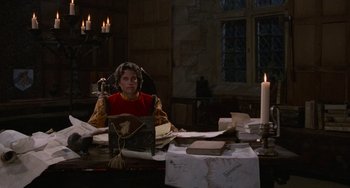 Movie still from “The Princess Bride” (1987), directed by Rob Reiner – A woman sitting at a table with a stack of papers and candles; Medium shot, High angle