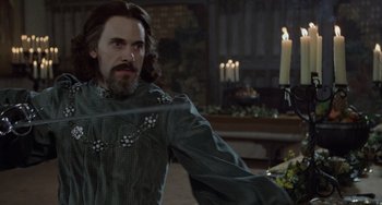 Movie still from “The Princess Bride” (1987), directed by Rob Reiner – A man with long hair and a beard is holding a sword in his hand; Medium shot, Over the shoulder angle