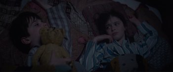 Movie still from “The Railway Children Return” (2022), directed by Morgan Matthews – A young girl laying in bed with a teddy bear; Medium shot, High angle