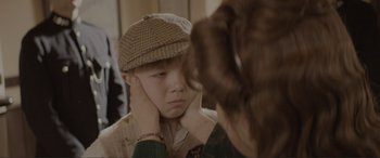 Movie still from “The Railway Children Return” (2022), directed by Morgan Matthews – A young boy wearing a brown hat looking in the mirror; Close Up shot, Over the shoulder angle