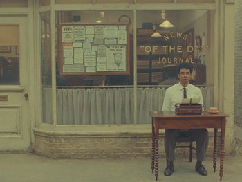 A man sitting at a desk in front of an old fashioned typewriter
