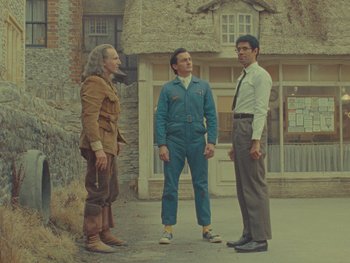 Movie still from “The Rat Catcher” (2023), directed by Wes Anderson – A group of men standing next to each other on a sidewalk; Wide shot, Low angle