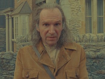 Movie still from “The Rat Catcher” (2023), directed by Wes Anderson – An old man with long hair and a beard; Close Up shot, Over the shoulder angle