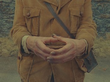Movie still from “The Rat Catcher” (2023), directed by Wes Anderson – A person holding a cookie in their hands; Extreme Close Up shot, Overhead angle