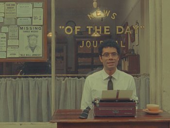 Movie still from “The Rat Catcher” (2023), directed by Wes Anderson – A man sitting at a desk with a typewriter; Medium shot, Low angle