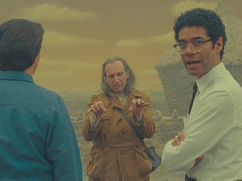 Movie still from “The Rat Catcher” (2023), directed by Wes Anderson – A group of men standing next to each other in a field; Medium shot, Over the shoulder angle