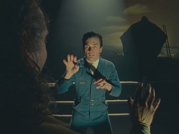 Movie still from “The Rat Catcher” (2023), directed by Wes Anderson – A man holding a knife in his hands; Medium shot, Low angle