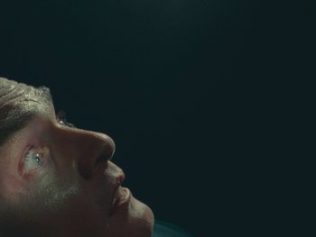 Movie still from “The Rat Catcher” (2023), directed by Wes Anderson – A person's face in the dark; Extreme Close Up shot, Overhead angle