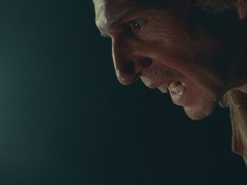 Movie still from “The Rat Catcher” (2023), directed by Wes Anderson – A man's face with a tooth brush in his mouth; Extreme Close Up shot, Low angle