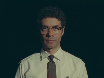 Movie still from “The Rat Catcher” (2023), directed by Wes Anderson – A man in a white shirt and a brown tie; Close Up shot, Low angle